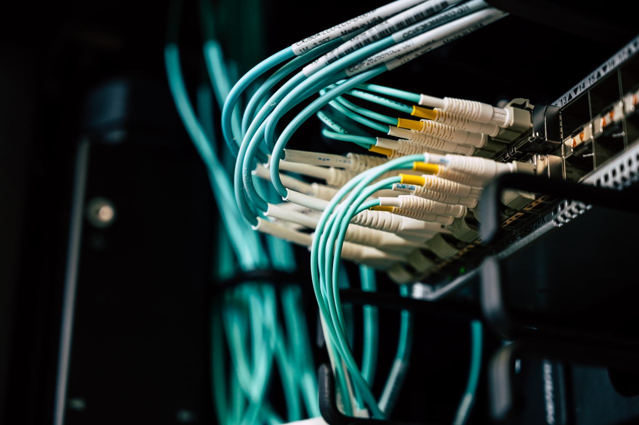 about-header Detailed view of network cables plugged into a server rack in a data center.